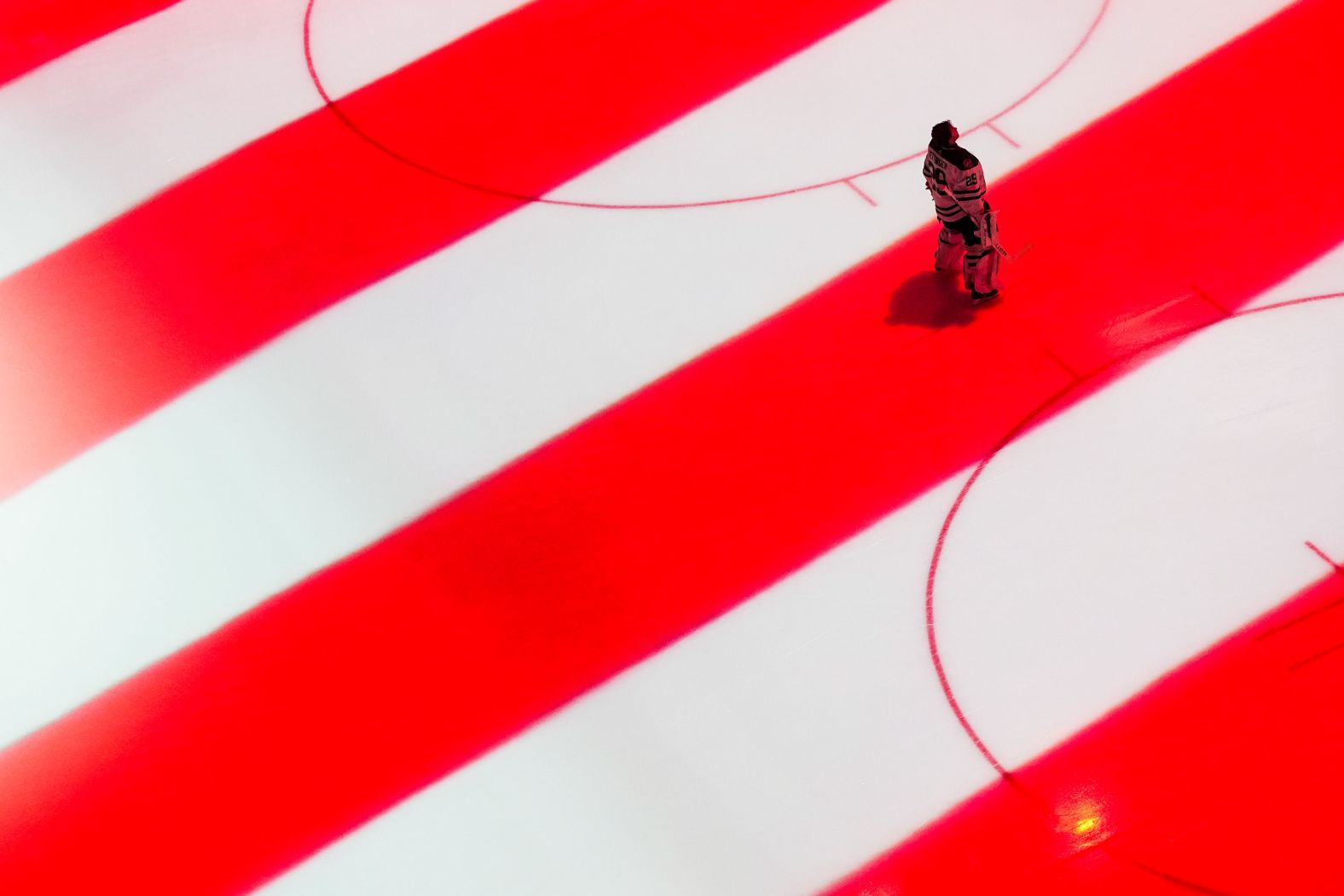 The American flag is projected onto the ice as Dallas Stars goaltender Jake Oettinger stands for the national anthem before an NHL game in Seattle on Saturday, March 30.