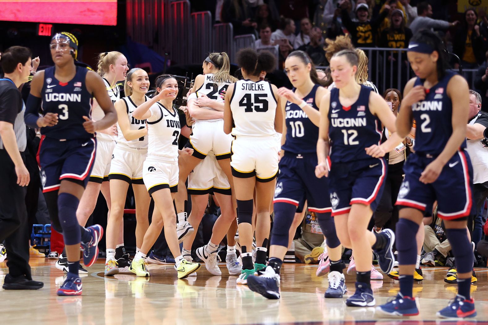 The Hawkeyes celebrate as the Huskies walk off the court after the game.