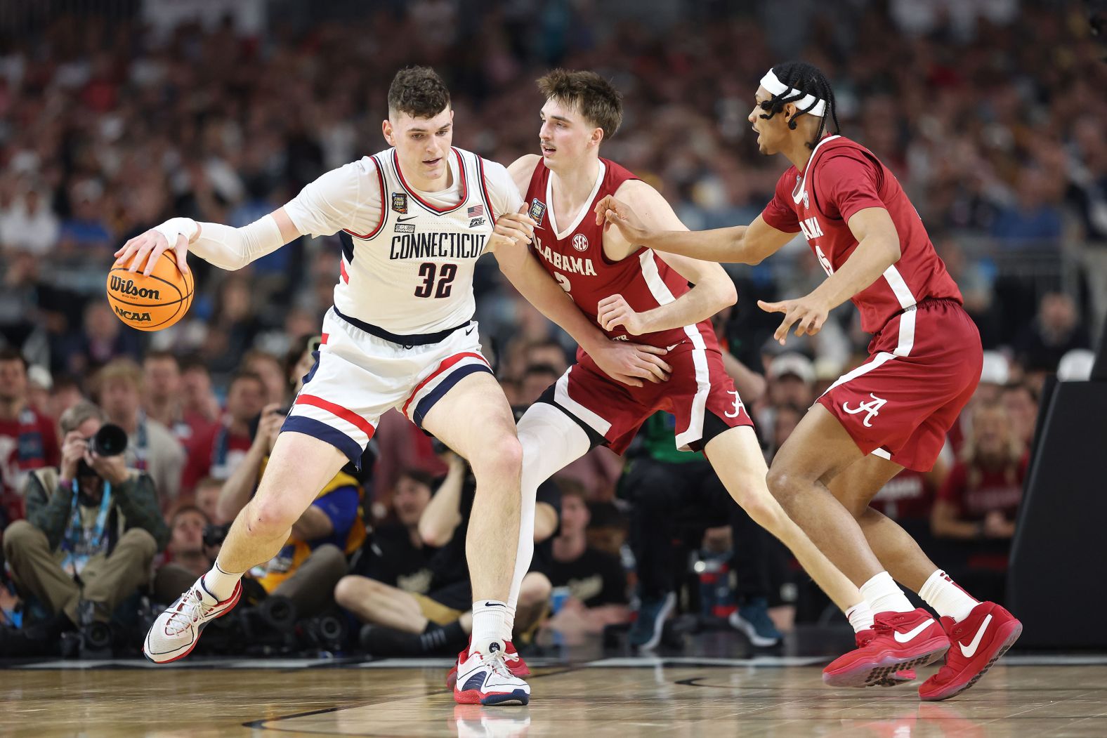 Clingan dribbles the ball under pressure from the Crimson Tide.