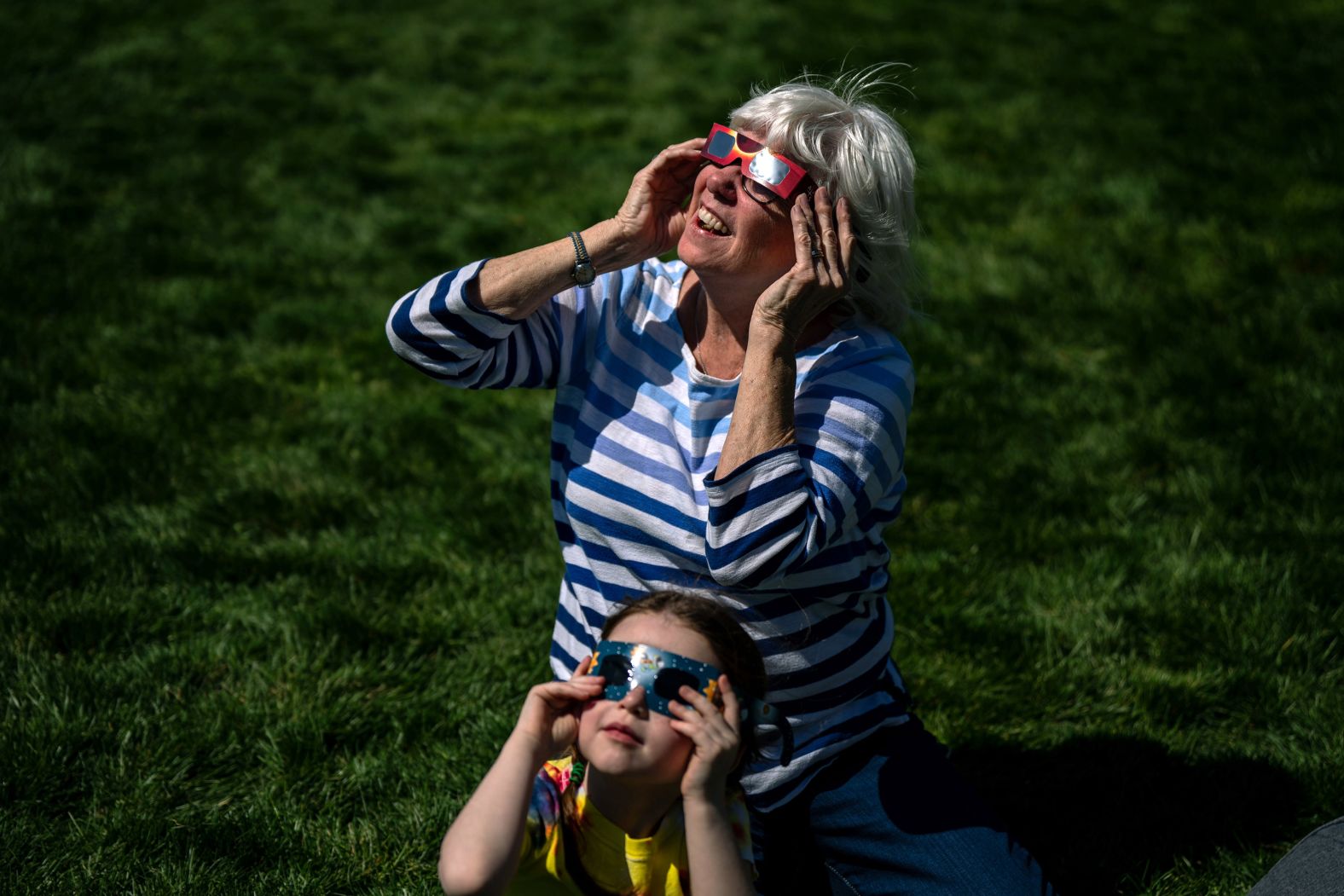 Barbara McLaughlin and her granddaughter test out their eclipse glasses as they wait on the National Mall in Washington, DC.