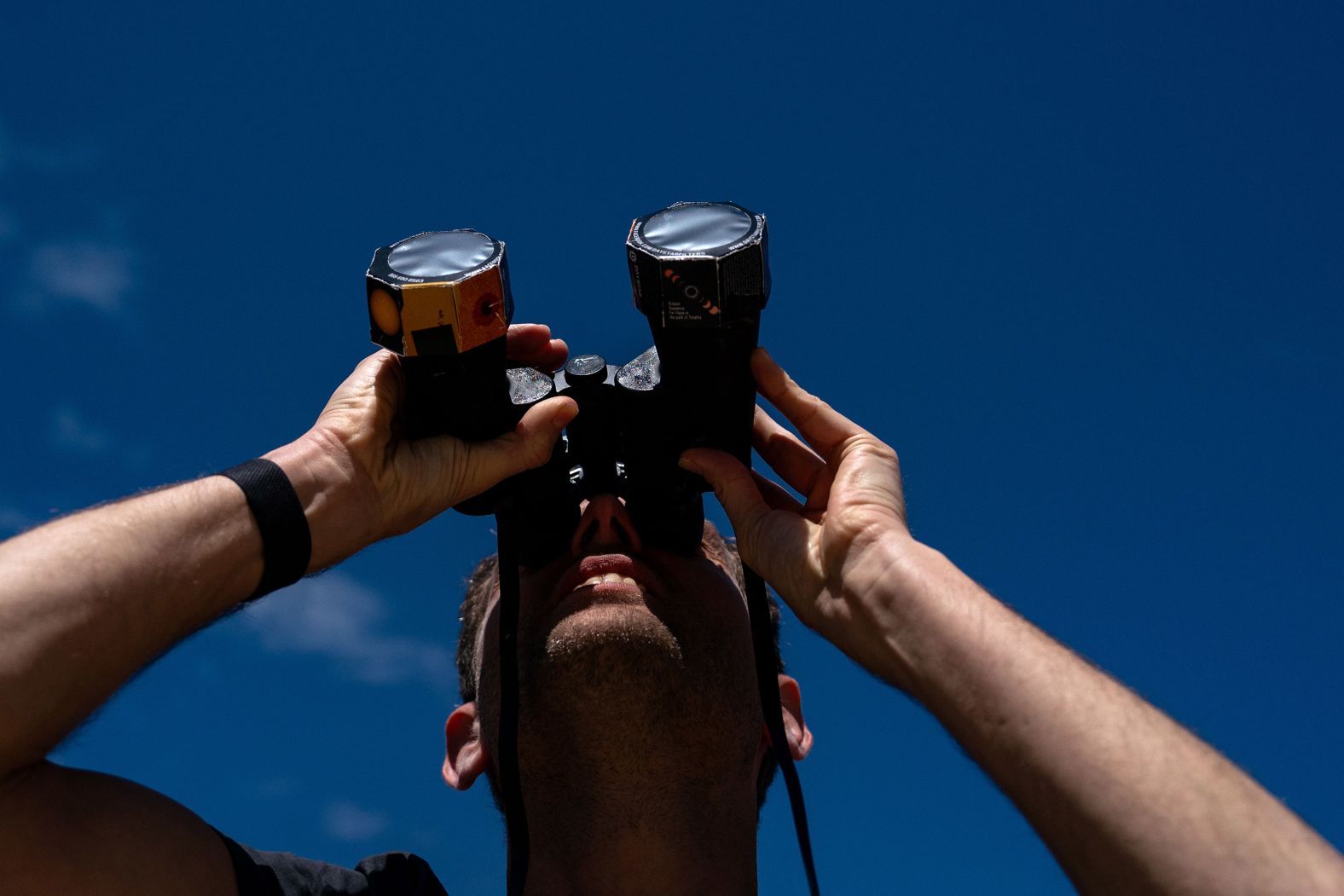 Frederik De Vries, one of the eclipse watchers on the National Mall in Washington, DC, looks up at the sun using binoculars outfitted with solar film.