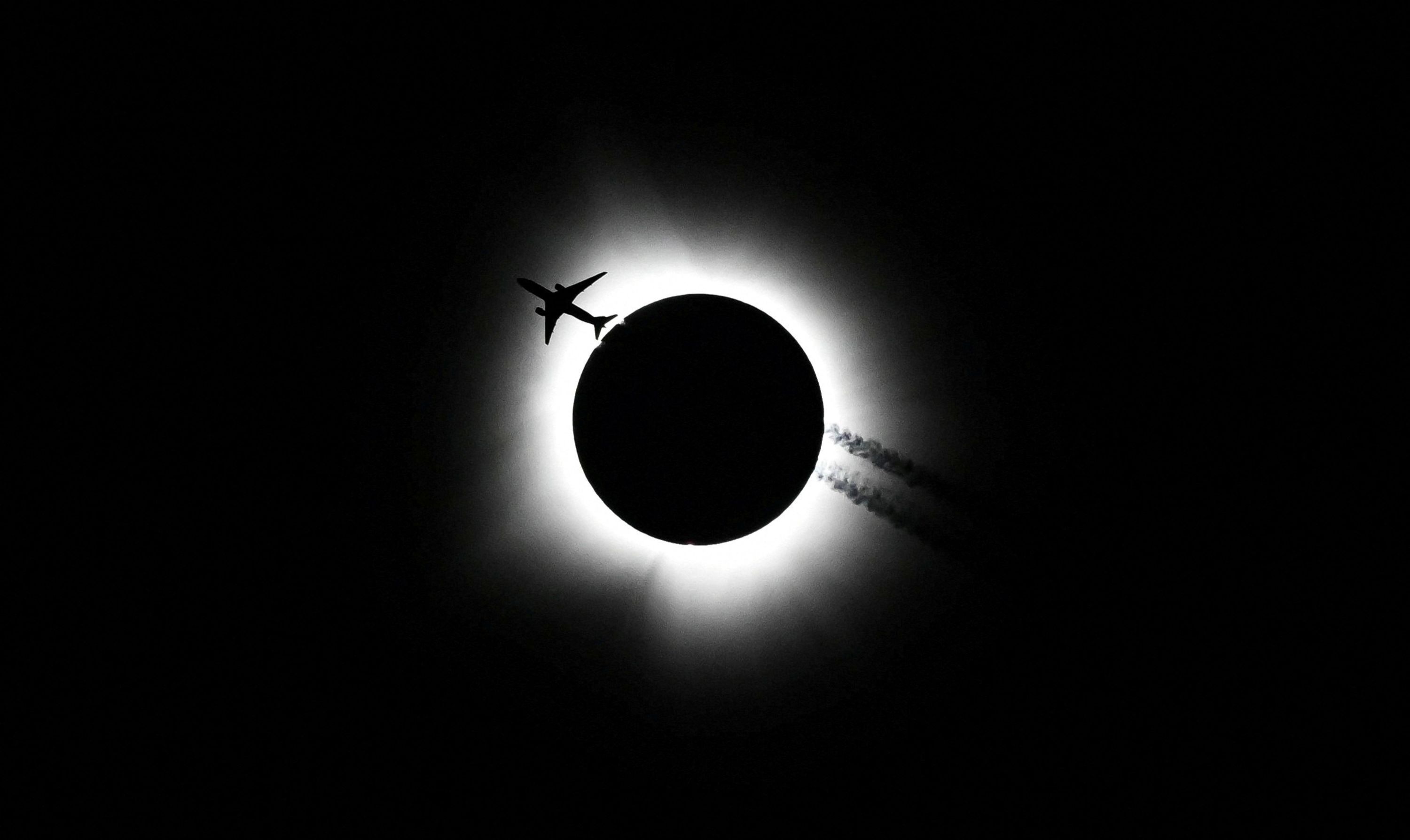 An airplane passes by as the total solar eclipse is seen from Bloomington, Indiana, on Monday, April 8.