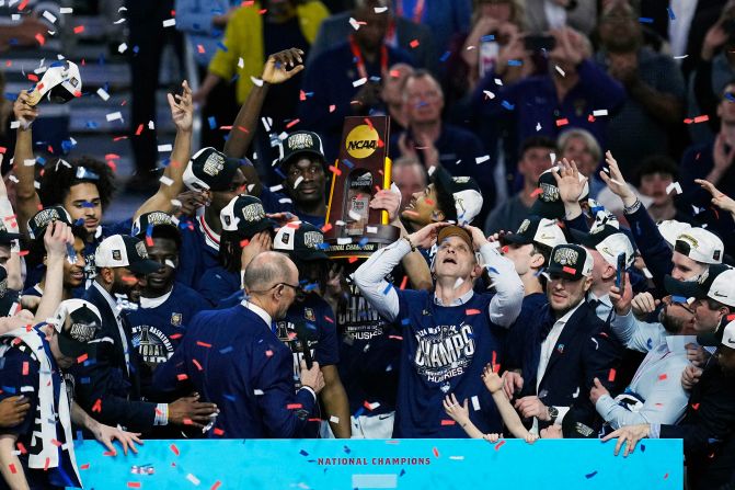 Confetti falls as the Huskies hoist the trophy while celebrating their national championship win.