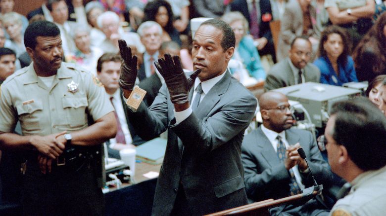 O.J. Simpson looks at a new pair of Aris extra-large gloves which the prosecutors had him put on for the jury 21 June 1995 during his double murder trial in Los Angeles. The gloves were the same type found at the Bundy murder scene and the O.J. Simpson estate.