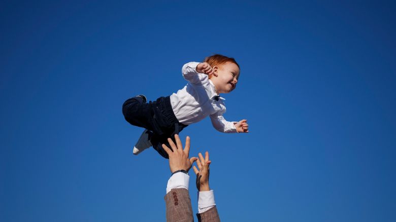 A Muslim man playfully throws a baby in the air at the end of Eid al-Fitr prayers in Bucharest, Romania, Wednesday, April 10, 2024. Members of the Romanian Muslim community joined prayers at the Dinamo stadium in the Romanian capital, in the largest Muslim public gathering of the year. Eid al-Fitr marks the end of the holy fasting month of Ramadan. (AP Photo/Andreea Alexandru)