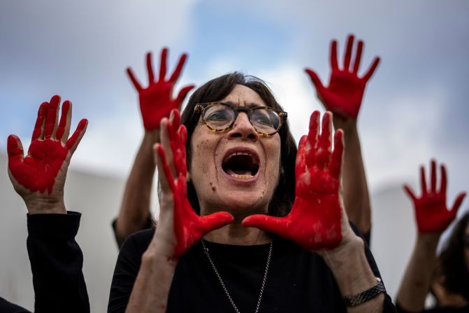 Family and supporters of hostages held in Gaza scream and hold up their hands, painted red to symbolize blood, in Tel Aviv, Israel, on Sunday, April 7, to call for the captives' release and mark six months since the October 7 Hamas attacks.