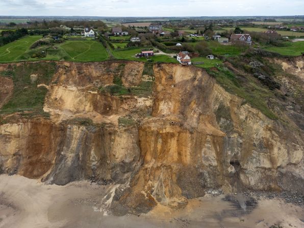 A house partially hangs over a cliff edge in Trimingham, England, on Monday, April 8, following rapid coastal erosion.