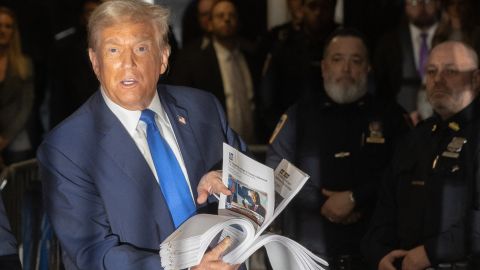 Former US President Donald Trump holds press clippings as he speaks to members of the media during his trial for allegedly covering up hush money payments linked to extramarital affairs, at Manhattan Criminal Court in New York City on April 18, 2024. Trump's criminal trial resumed Thursday with Judge Juan Merchan seeking to complete jury selection. Moving the US into uncharted waters, it is the first criminal trial of a former US president, one who is also battling to retake the White House in November. (Photo by JEENAH MOON / POOL / AFP) (Photo by JEENAH MOON/POOL/AFP via Getty Images)