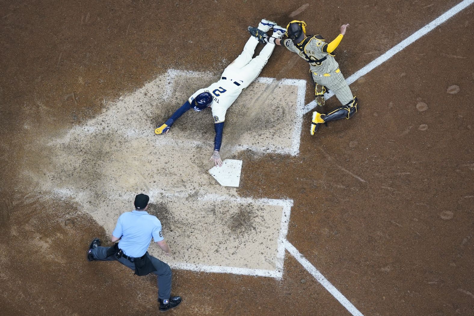 Milwaukee Brewers second baseman Brice Turang slides safely past San Diego Padres catcher Kyle Higashioka during a game in Milwaukee on Wednesday, April 17.