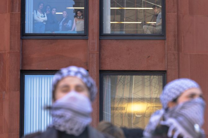 People watch from a window as New York University students set up a tent encampment on April 22.