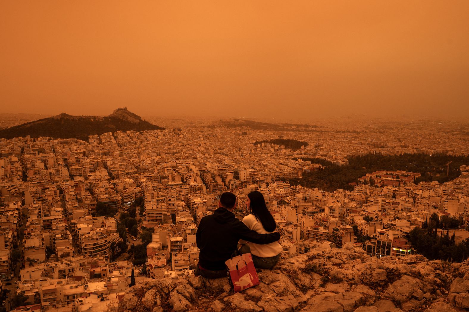 A couple sits on the Tourkovounia hills as southerly winds <a href="index.php?page=&url=https%3A%2F%2Fwww.cnn.com%2F2024%2F04%2F23%2Feurope%2Fweather-finland-snow-sahara-dust-greece-intl-latam%2Findex.html" target="_blank">carry waves of Saharan dust</a> through Athens, Greece, on Tuesday, April 23. Clouds of dust moving from northern Africa to Greece and other regions is a phenomenon that occasionally occurs, bringing limited visibility and prompting warnings of breathing risks.