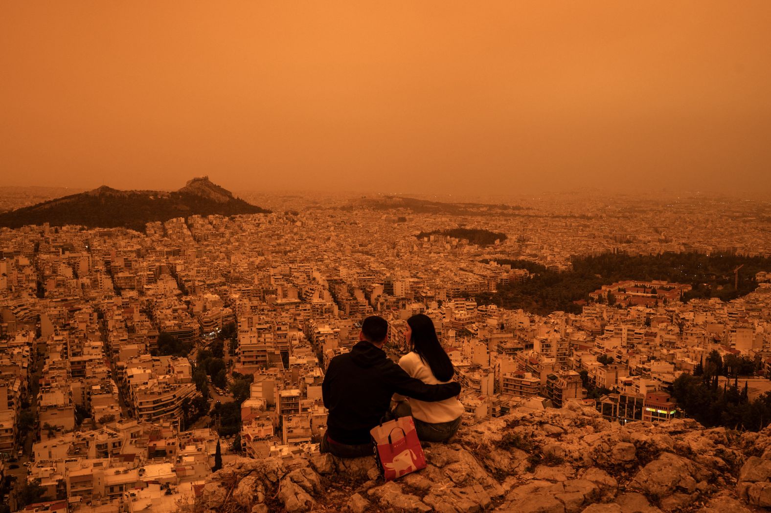 A couple sits on the Tourkovounia hills as southerly winds <a href="https://www.cnn.com/2024/04/23/europe/weather-finland-snow-sahara-dust-greece-intl-latam/index.html" target="_blank">carry waves of Saharan dust</a> through Athens, Greece, on Tuesday, April 23. Clouds of dust moving from northern Africa to Greece and other regions is a phenomenon that occasionally occurs, bringing limited visibility and prompting warnings of breathing risks.