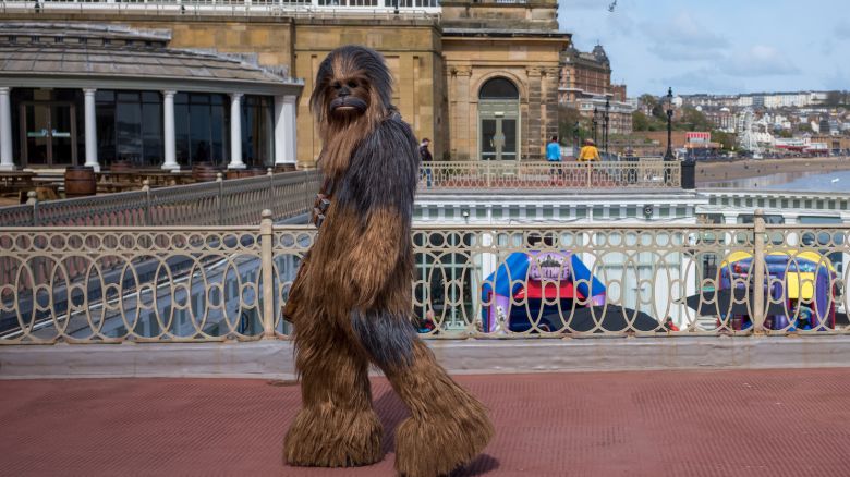 SCARBOROUGH, ENGLAND - APRIL 21: A man dressed as the Chewbacca character from the Star Wars film walks through Scarborough Spa on day two of the Scarborough Sci Fi weekend on April 21, 2024 in Scarborough, England. The North Yorkshire seaside town hosts the event at the Scarborough Spa complex and showcases many areas of Sci-Fi fandom to entertain visitors and enthusiasts including guest star appearances, panel discussions, gaming, cosplay, props, comic books and merchandise stalls with many of those attending wearing costumes and outfits of their favourite Sci-Fi characters. (Photo by Ian Forsyth/Getty Images)