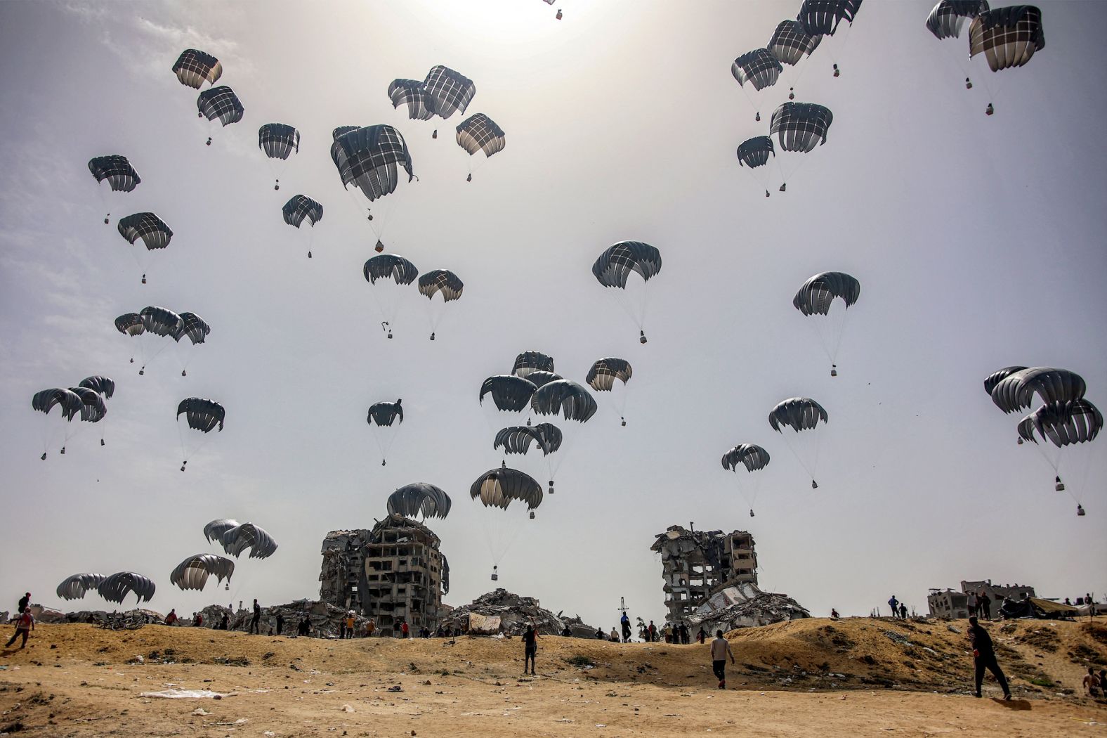 People rush to humanitarian aid packages being dropped over northern Gaza on Tuesday, April 23.