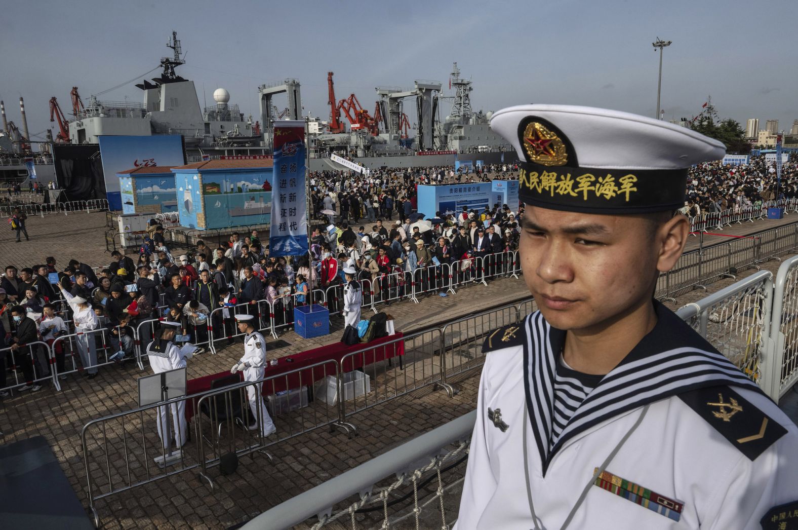 A sailor stands on the deck of the Guyiyang destroyer as members of the public line up to visit the ship in Qingdao, China, on Saturday, April 20. China was marking the 75th anniversary of the country's navy.