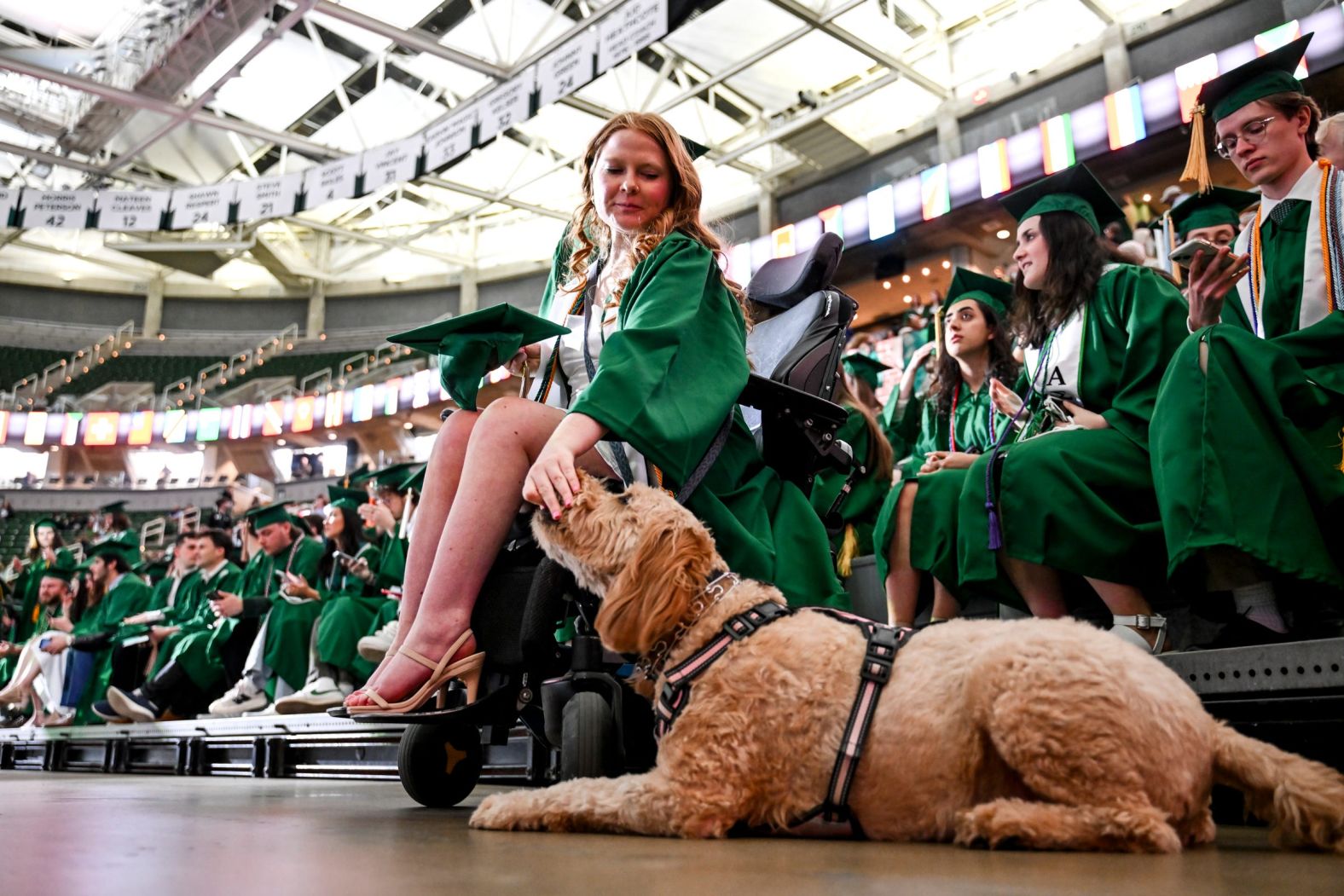 Accounting graduate Jordan Zmich pets her service dog Murphy, a goldendoodle, during Michigan State University's spring convocation ceremony on Friday, April 26.