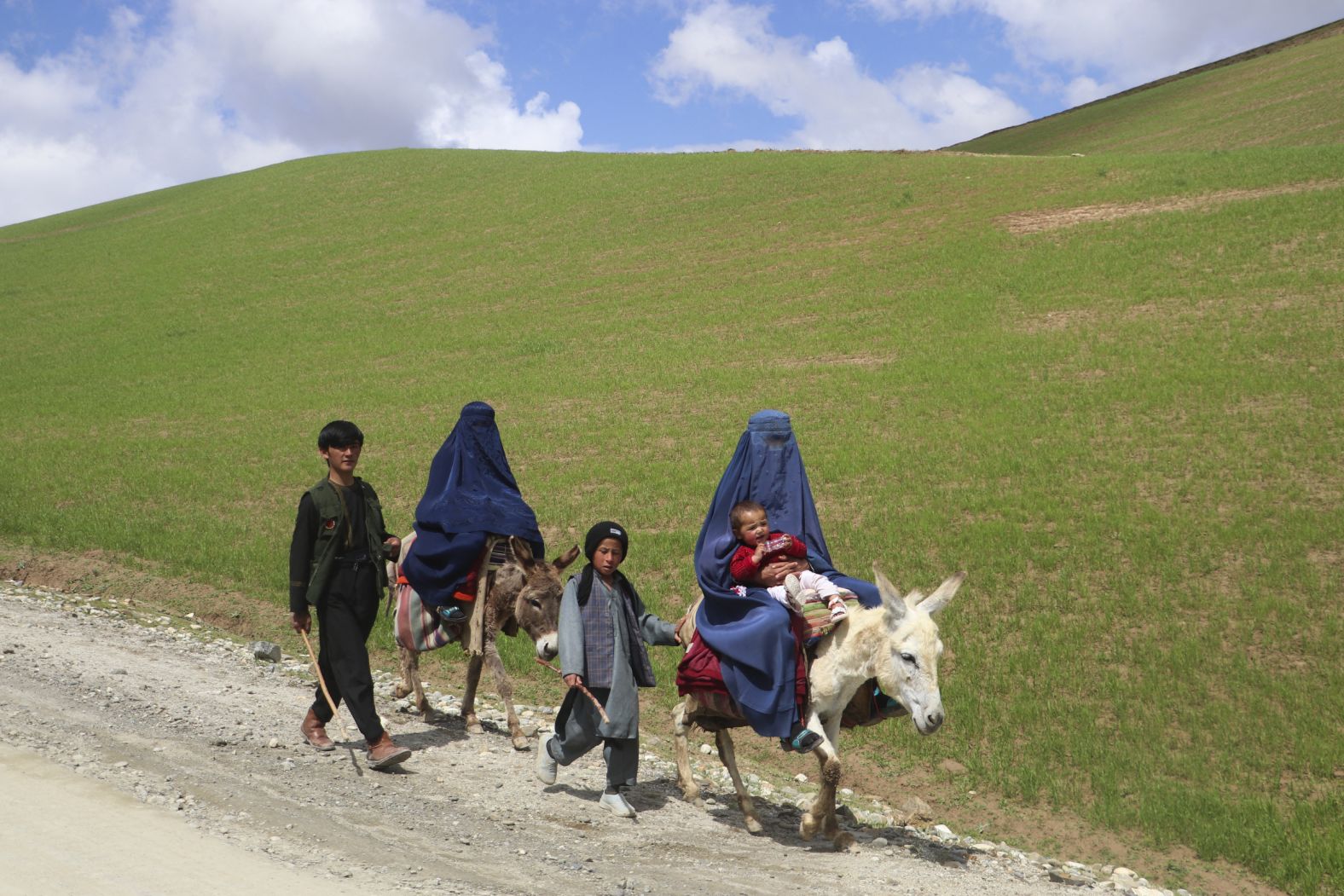 Women ride donkeys alongside children on a road near the Afghan village of Shah Mari on Wednesday, May 1.