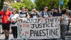 Students march while holding a sign during the pro-Palestine student protests that have turned into an encampment at George Washington University's Yard in a protest movement that has spread across universities in the U.S, demonstrating against Israeli military action in Gaza and calling on their university to stop doing business with companies they see as supporting the war on Wednesday, May 01, 2024. Despite the police crackdowns, the students have continued to rally and call for a ceasefire in Israel's war on Gaza. (Photo by Amid Farahi / Middle East Images / Middle East Images via AFP) (Photo by AMID FARAHI/Middle East Images/AFP via Getty Images)