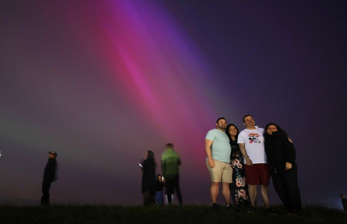 People pose for a photograph with the aurora borealis in Crosby, England, on May 10.
