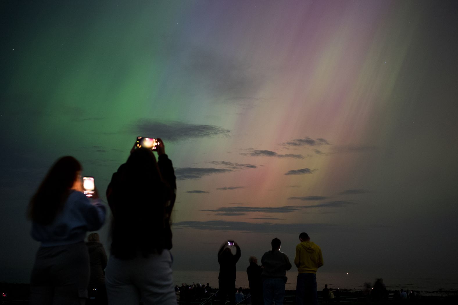 People photograph the northern lights from Whitley Bay, England, on May 10.