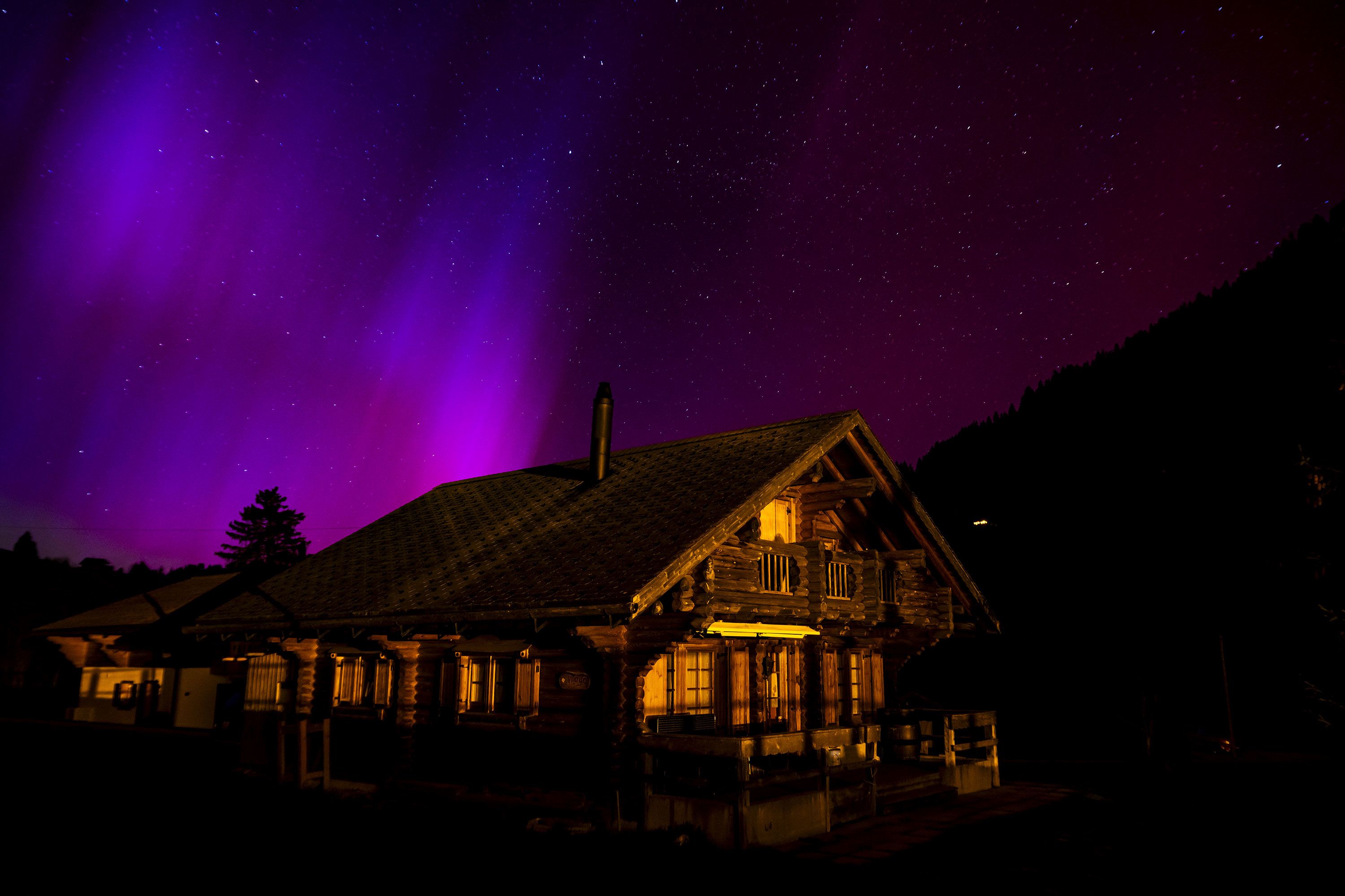 The aurora borealis glows in the night sky over the mountains in Le Col des Mosses pass، Ormont-Dessous، Switzerland، during the early hours of May 11.