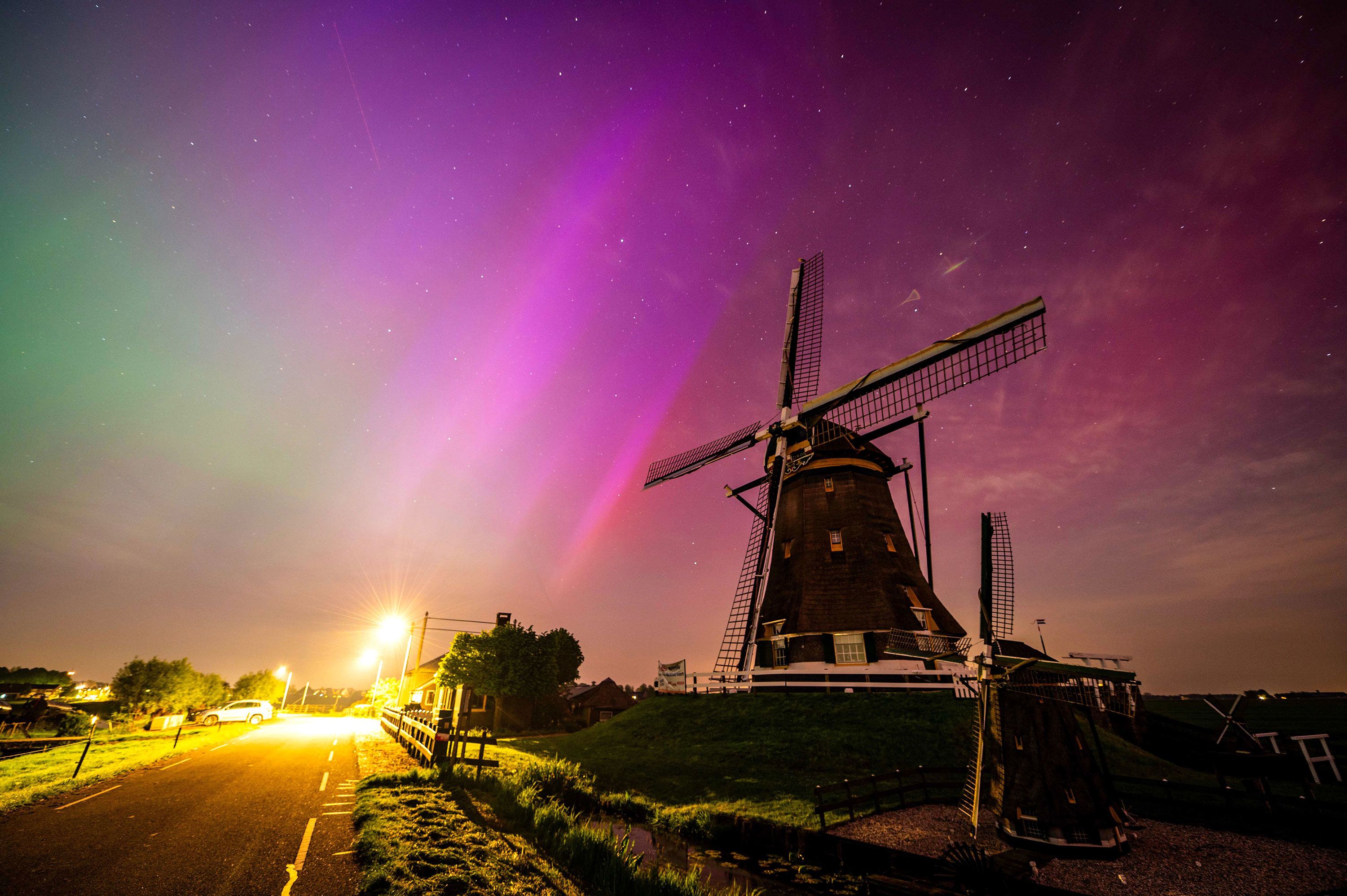 The northern lights shine in the night sky above the Molenviergang in Aarlanderveen، the Netherlands، early May 11.