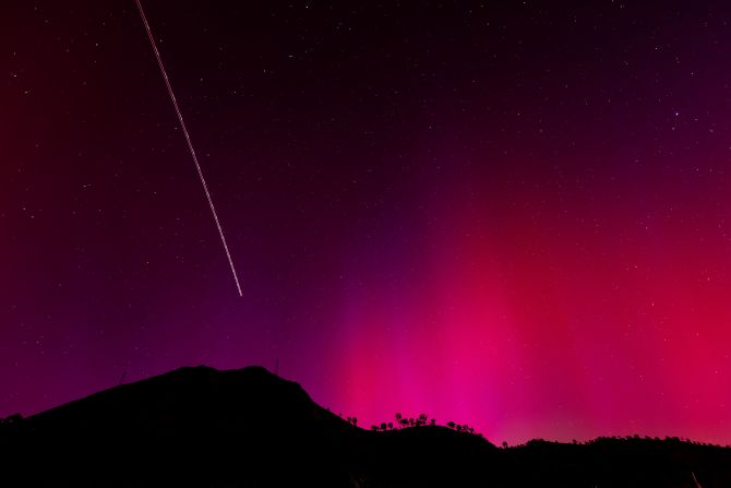 In this long exposure photo, the blinking lights of a plane streak through the aurora borealis over Lake Berryessa, California, on May 11.