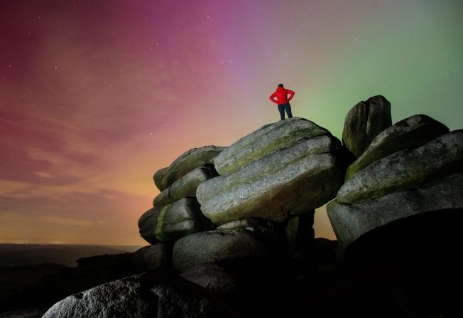 A person watches the northern lights from atop a rock formation near Sheffield, England, on May 11. 