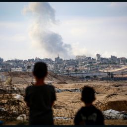 Boys watch smoke billowing during Israeli strikes east of Rafah in the southern Gaza Strip on May 13, 2024.