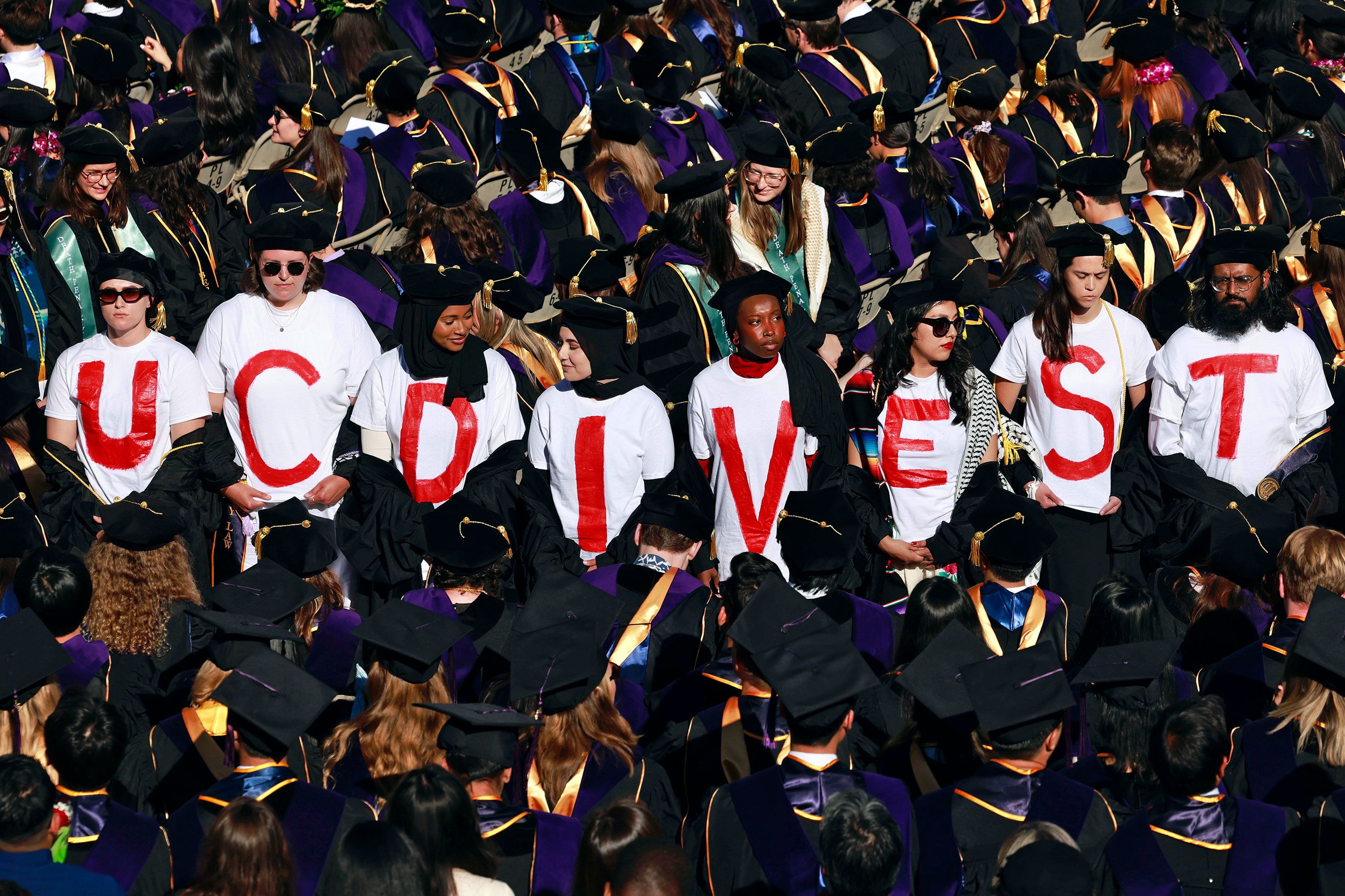 Graduates from the UC Berkeley School of Law wear T-shirts spelling out 'UC DIVEST'.