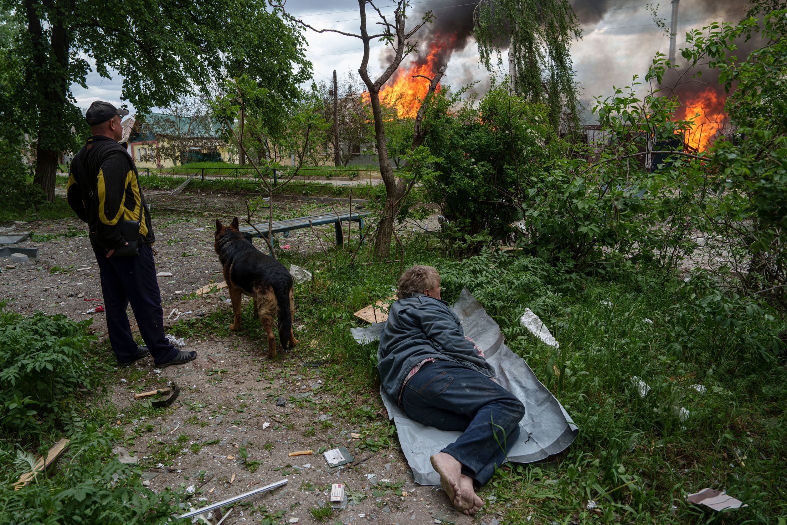 A man lies on the ground as he watches his burning house, which was destroyed by a Russian airstrike in Vovchansk, Ukraine, on Saturday, May 11.