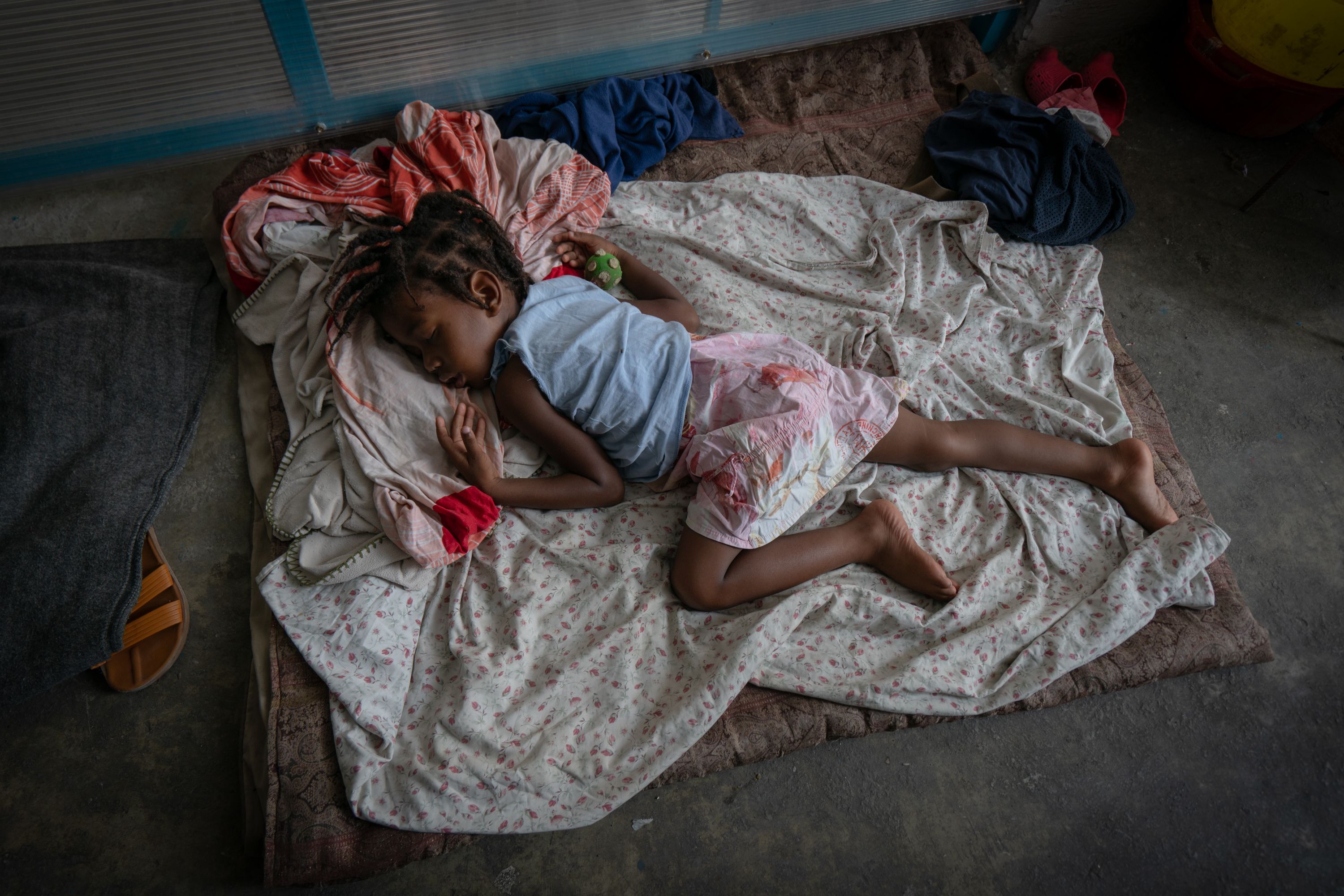 A young girl sleeps on the floor of a corridor inside the Lycée Marie-Jeanne high school in Port-au-Prince. The school is now occupied by people who've fled from gang violence.