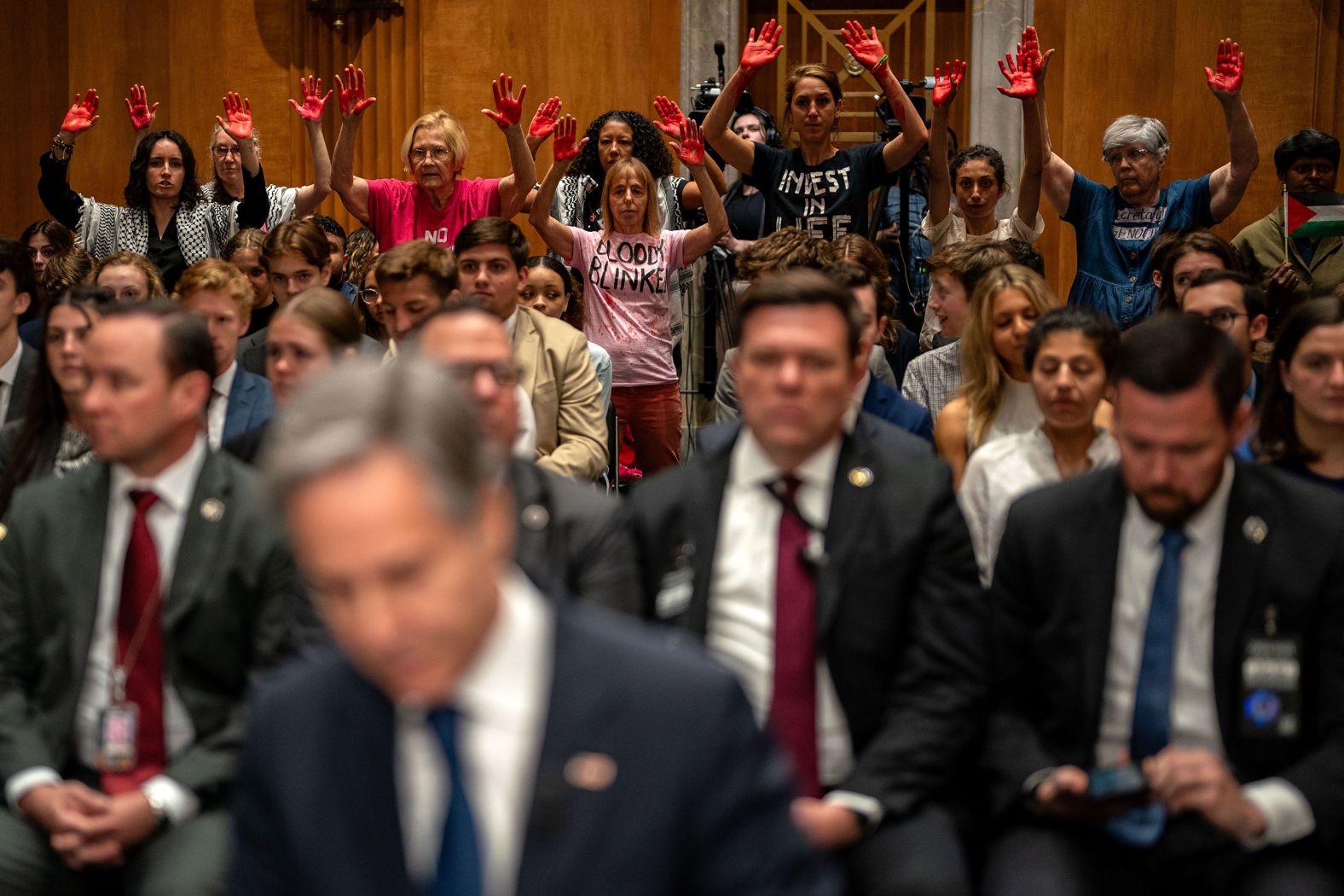 Pro-Palestinian demonstrators hold up their red-painted hands as US Secretary of State Antony Blinken, seen in the foreground, arrives for a <a href="index.php?page=&url=https%3A%2F%2Fwww.cnn.com%2F2024%2F05%2F21%2Fpolitics%2Fblinken-congress-penalize-international-criminal-court%2Findex.html" target="_blank">Senate Foreign Relations Committee hearing</a> in Washington, DC, on Tuesday, May 21. Blinken said he wants to work with Congress on legislation to penalize the International Criminal Court after it <a href="index.php?page=&url=https%3A%2F%2Fwww.cnn.com%2F2024%2F05%2F20%2Fmiddleeast%2Ficc-israel-hamas-arrest-warrant-war-crimes-intl%2Findex.html" target="_blank">applied for arrest warrants</a> for Israeli Prime Minister Benjamin Netanyahu and Defense Minister Yoav Gallant.