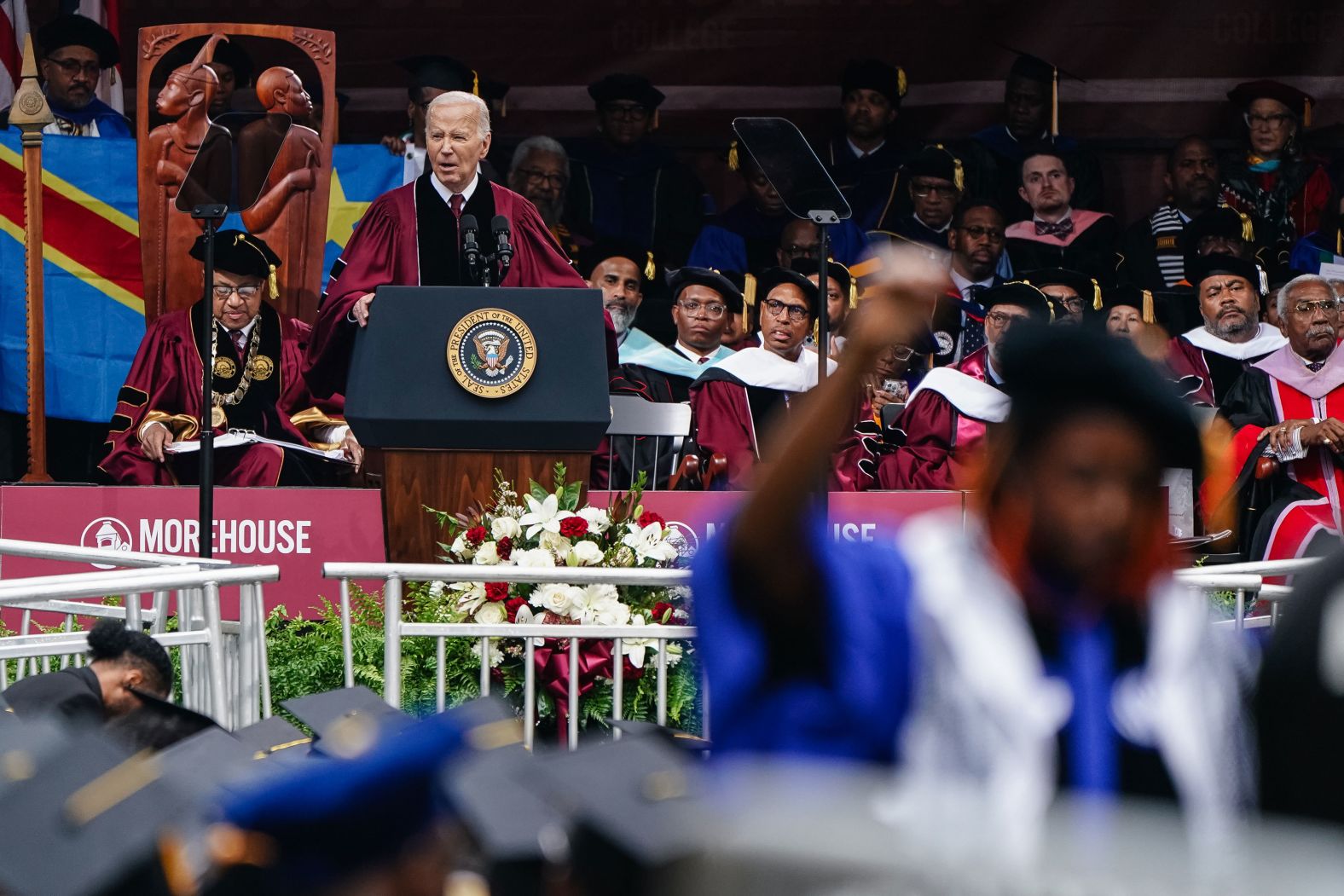 US President Joe Biden gives a <a href="index.php?page=&url=https%3A%2F%2Fwww.cnn.com%2F2024%2F05%2F19%2Fpolitics%2Fbiden-morehouse-commencement%2Findex.html" target="_blank">commencement address at Morehouse College</a> in Atlanta on Sunday, May 19. In the foreground, a faculty member raises her fist in protest of the war in Gaza. During his speech, Biden delivered a forceful call for a ceasefire between Israel and Hamas paired with the release of Israeli hostages.