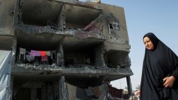 A Palestinian woman walks past a house destroyed by an Israeli strike, in Rafah, on May 22, 2024.