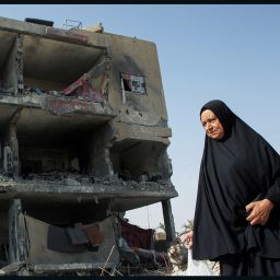 A Palestinian woman walks past a house destroyed by an Israeli strike, in Rafah, on May 22, 2024.