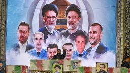 CORRECTION / An Iranian man reads a prayer over the coffin of late president Ebrahim Raisi, backdropped by a mural of those who were killed with him in a helicopter crash,  during a funeral ceremony at the Imam Reza shrine, in the city of Mashhad, on May 23, 2024. Raisi and seven members of his entourage, including foreign minister Hossein Amir-Abdollahian, were killed in a helicopter crash on a fog-shrouded mountainside in Iran on May 19. (Photo by Sadegh NIKGOSTAR / FARS NEWS AGENCY / AFP) / "The erroneous mention[s] appearing in the metadata of this photo by Sadegh NIKGOSTAR has been modified in AFP systems in the following manner: [Pray over the coffins] instead of [..carry the coffin]. Please immediately remove the erroneous mention[s] from all your online services and delete it (them) from your servers. If you have been authorized by AFP to distribute it (them) to third parties, please ensure that the same actions are carried out by them. Failure to promptly comply with these instructions will entail liability on your part for any continued or post notification usage. Therefore we thank you very much for all your attention and prompt action. We are sorry for the inconvenience this notification may cause and remain at your disposal for any further information you may require." (Photo by SADEGH NIKGOSTAR/FARS NEWS AGENCY/AFP via Getty Images)