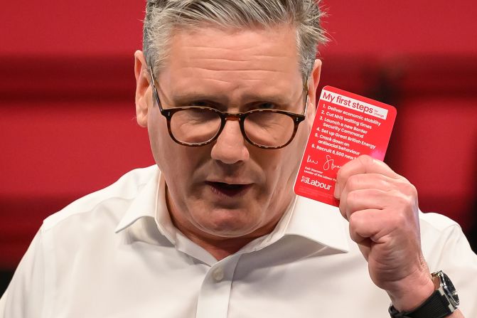 Starmer holds a card featuring six election pledges during a Labour event in Purfleet, England, in May 2024.