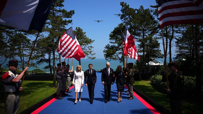 TOPSHOT - (From L) French President's wife Brigitte Macron, France's President Emmanuel Macron, US President Joe Biden and US First Lady Jill Biden arrive to attend the US ceremony marking the 80th anniversary of the World War II "D-Day" Allied landings in Normandy, at the Normandy American Cemetery and Memorial in Colleville-sur-Mer, which overlooks Omaha Beach in northwestern France, on June 6, 2024. The D-Day ceremonies on June 6 this year mark the 80th anniversary since the launch of 'Operation Overlord', a vast military operation by Allied forces in Normandy, which turned the tide of World War II, eventually leading to the liberation of occupied France and the end of the war against Nazi Germany. (Photo by Daniel Cole / POOL / AFP) (Photo by DANIEL COLE/POOL/AFP via Getty Images)