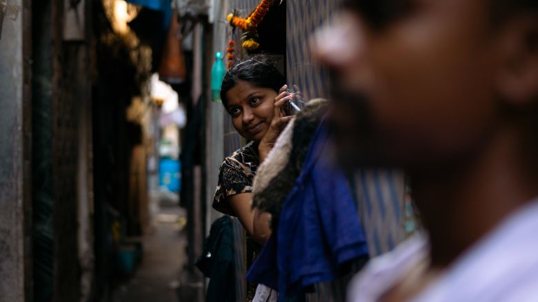A woman peeps out along a narrow alley of the Dharavi slum area of Mumbai, India, on April 14, 2024.