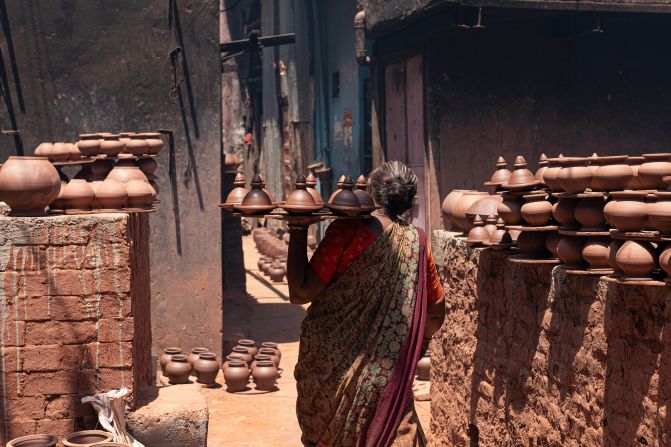 A woman carries a tray of clay pots in the Dharavi slum area of Mumbai, India, on April 14, 2024.