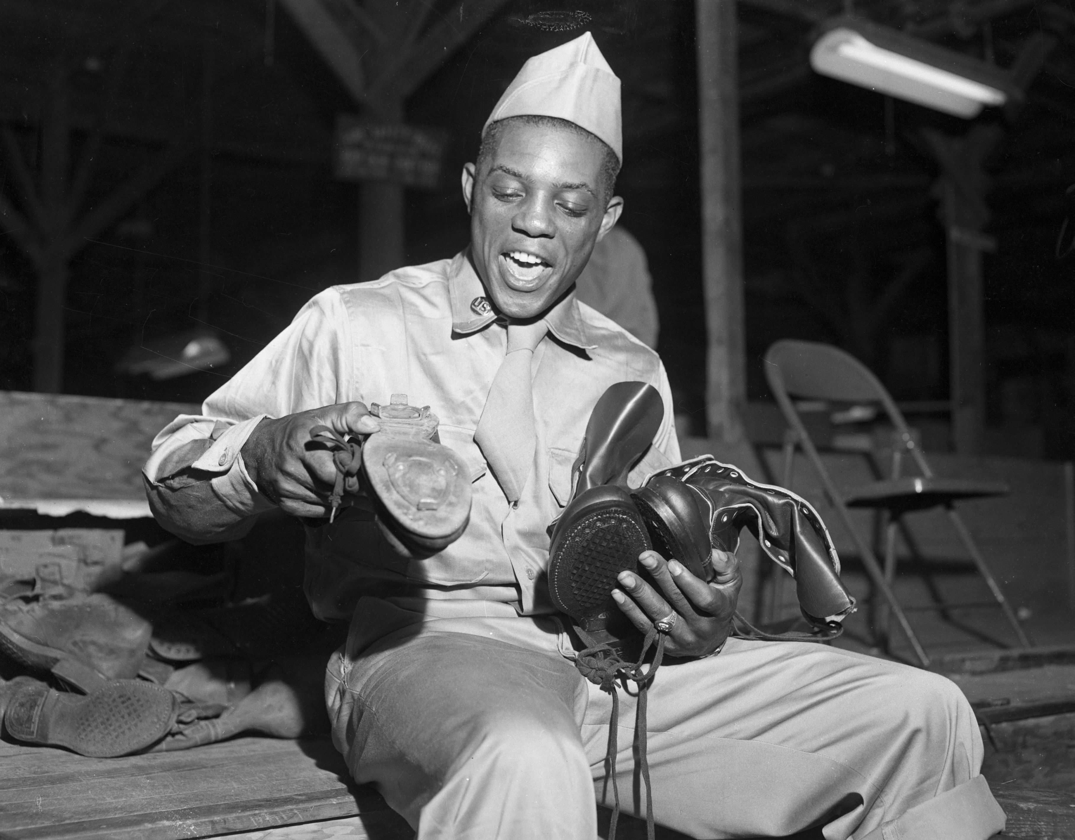 Mays bids goodbye to his baseball shoes, while also holding his Army-issued boots, at Camp Kilmer, New Jersey on May 29, 1952.