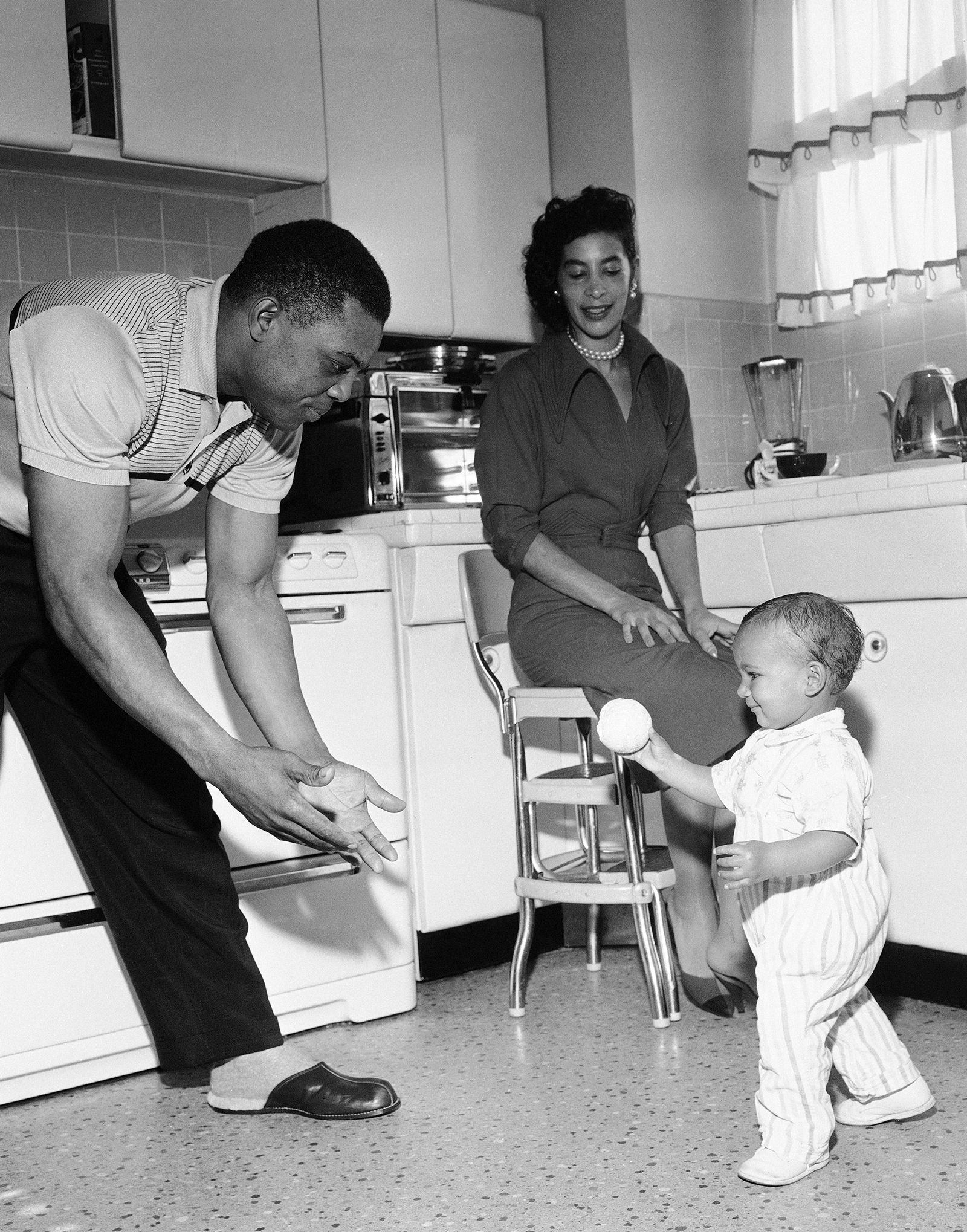 Mays plays catch with 14-month-old Herbert Henderson, in San Francisco, California on November 14, 1957.