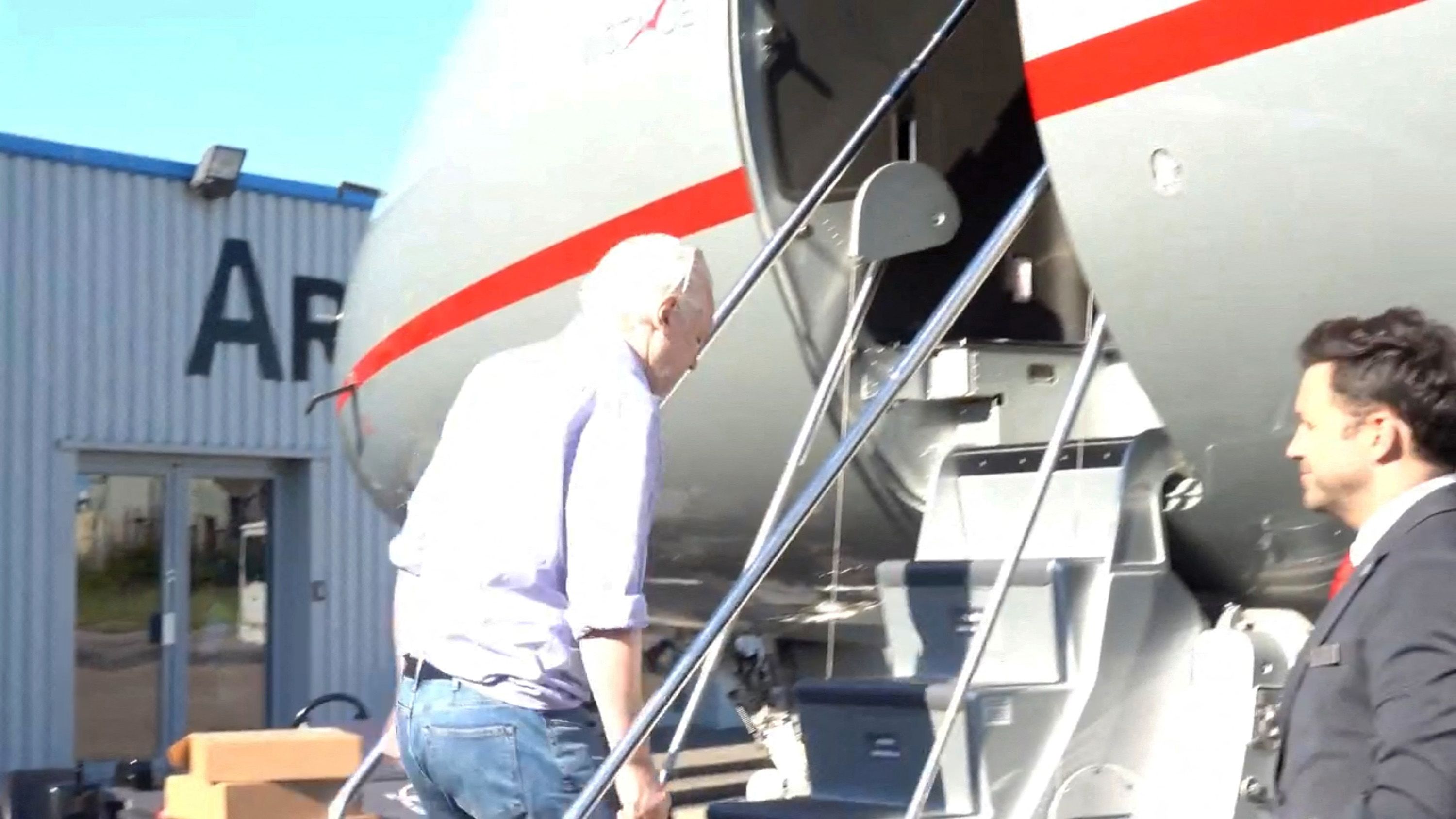 Assange boards a plane in London.