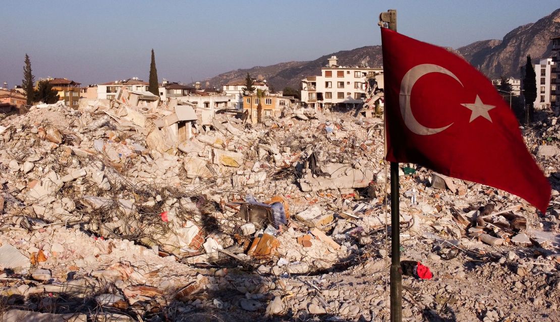 TOPSHOT - This aerial photograph taken on February 14, 2023 shows a Turkish flag waving over rubbles of destroyed buldings in Antakya, Hatay, a week after a deadly earthquake struck parts of Turkey and Syria. - More than 35,000 people were killed when the quake devastated swathes of Syria and neighbouring Turkey on February 6, at least 3,600 of them in Syria, according to government officials and emergency services in rebel areas. (Photo by Hassan AYADI / AFP) (Photo by HASSAN AYADI/AFP via Getty Images)