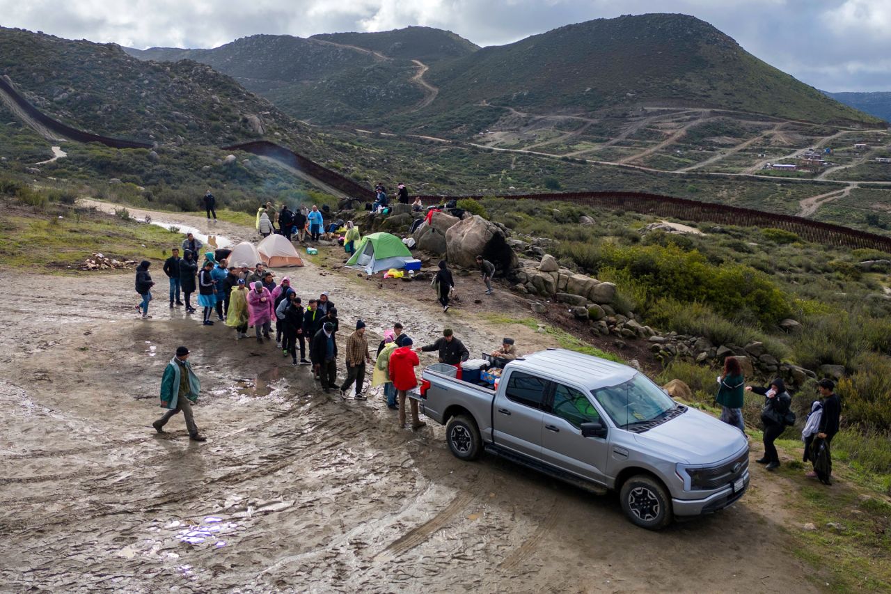 Humanitarian assistance volunteers distribute food to immigrants waiting to be taken into custody by US Border Patrol agents on March 7, in Campo, California. 