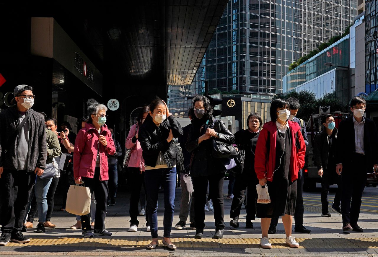 People wearing face mask walk at a downtown street in Hong Kong Friday, February 21.