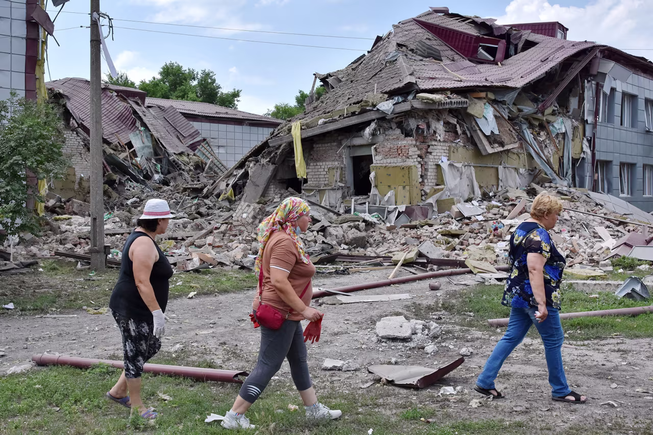 Residents walk by a school that was damaged by Russian shelling in Kamyshevakha, Ukraine, on July 2. 