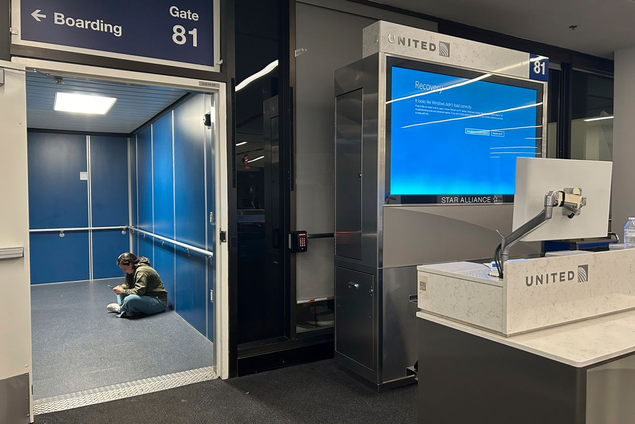 A traveler at Los Angeles International Airport sits in a jetway for a delayed United Airlines flight to Dulles International Airport due to a widespread global technology outage disrupting flights, banks, media outlets and companies around the world, on July 19, in Los Angeles. 