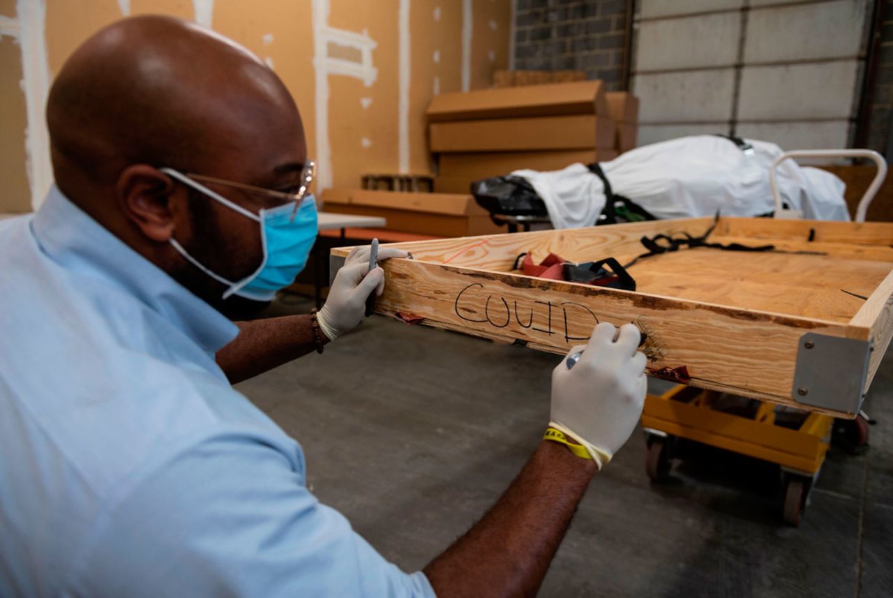 Reggie Elliott, a funeral transporter, writes on the side of a box before depositing the remains of a Covid-19 victim at Maryland Cremation Services in Millersville, Maryland on December 24.